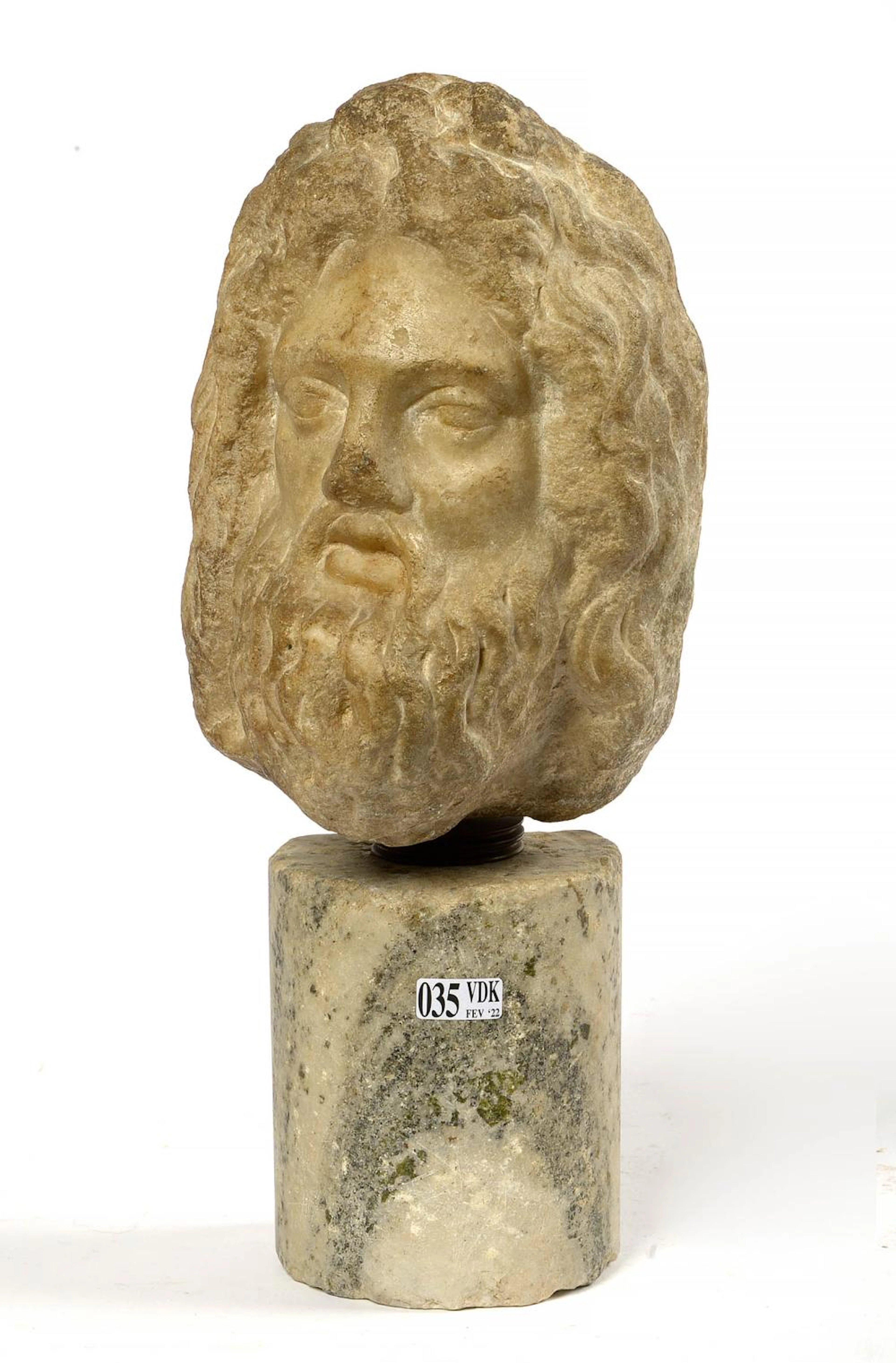 "Tête de divinité" en marbre blanc sculpté. Reposant sur une base