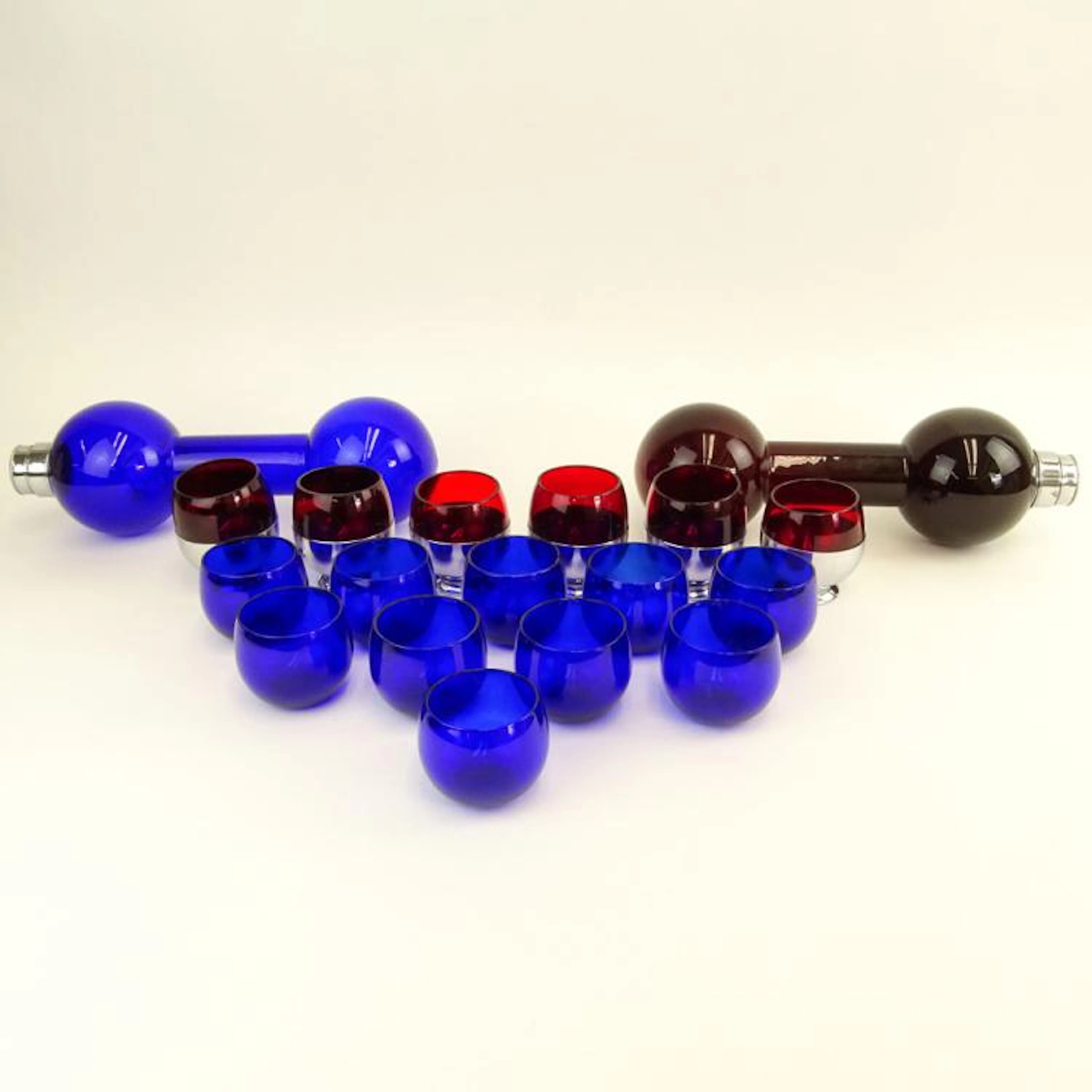 Art Deco circa 1930's Eighteen (18) Piece Cobalt Blue and Ruby Red Glass and Chase Company Liquor Set. Includes 2 barbell shaped cocktail shakers and 16 roly-poly cups, 6 Chase holders. Cup holders si