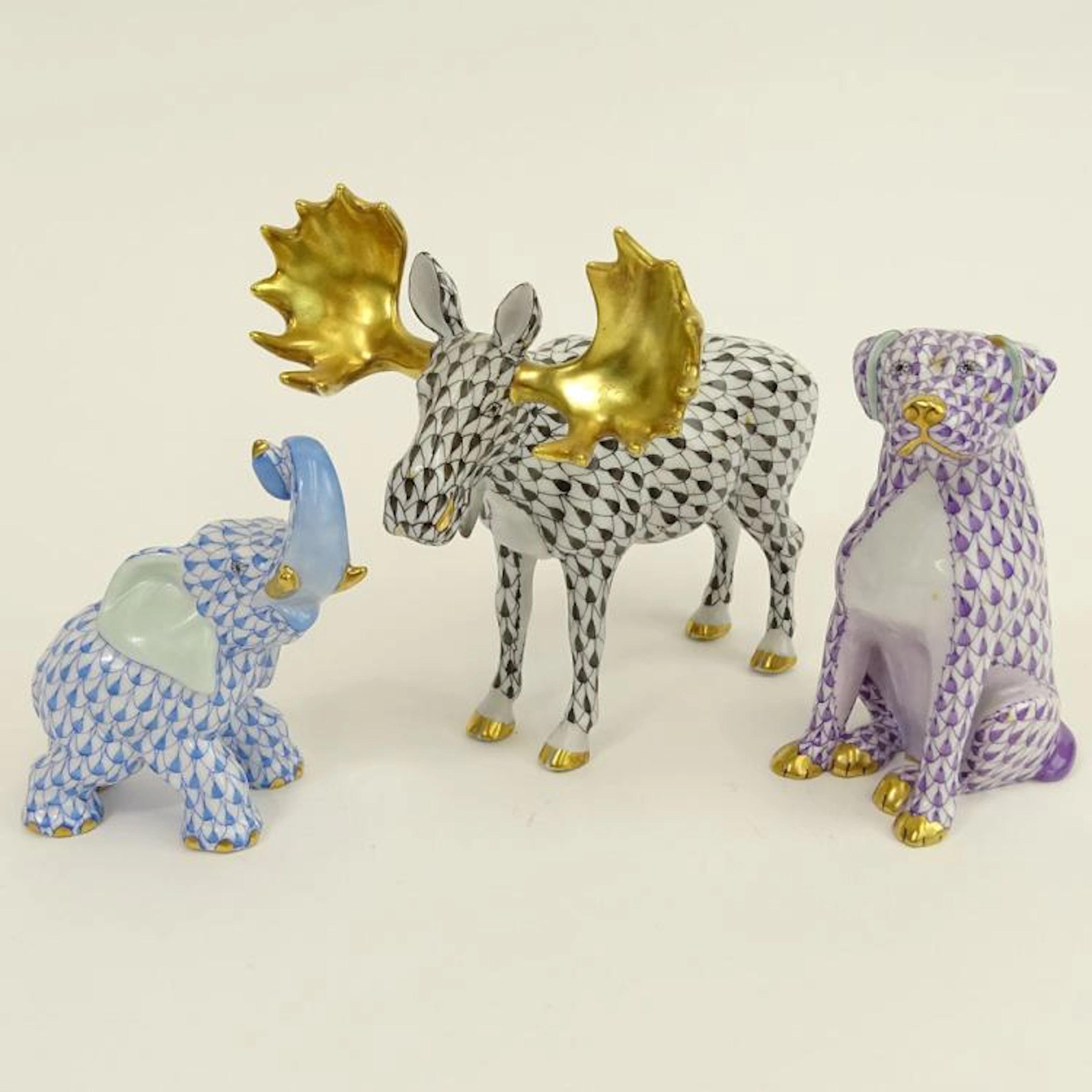 Lot of Three (3) Herend Porcelain Animal Figurines. Includes Moose, black fishnet 5-1/4"; seated dog, lavender fishnet; small elephant, blue fishnet. All pieces are signed appropriately. Good conditio