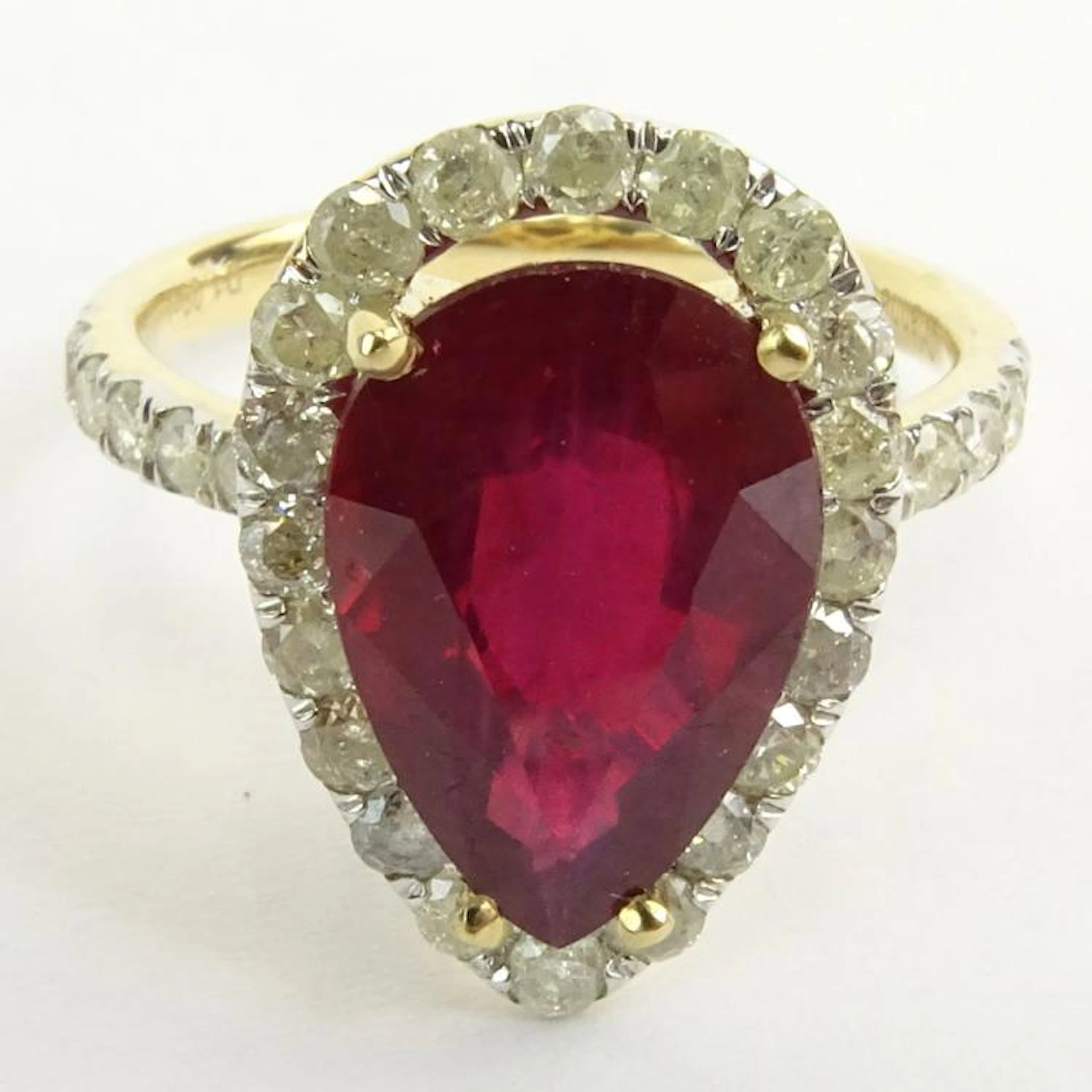 GGA Certified 5.61 Carat Pear Shape Ruby and 14 Karat Yellow Gold Ring Accented with 1.09 Carat Round Brilliant Cut Diamonds. Ruby I1 clarity. Diamonds I-K color, I1-I2 clarity. Signed 14K. Ring size 
