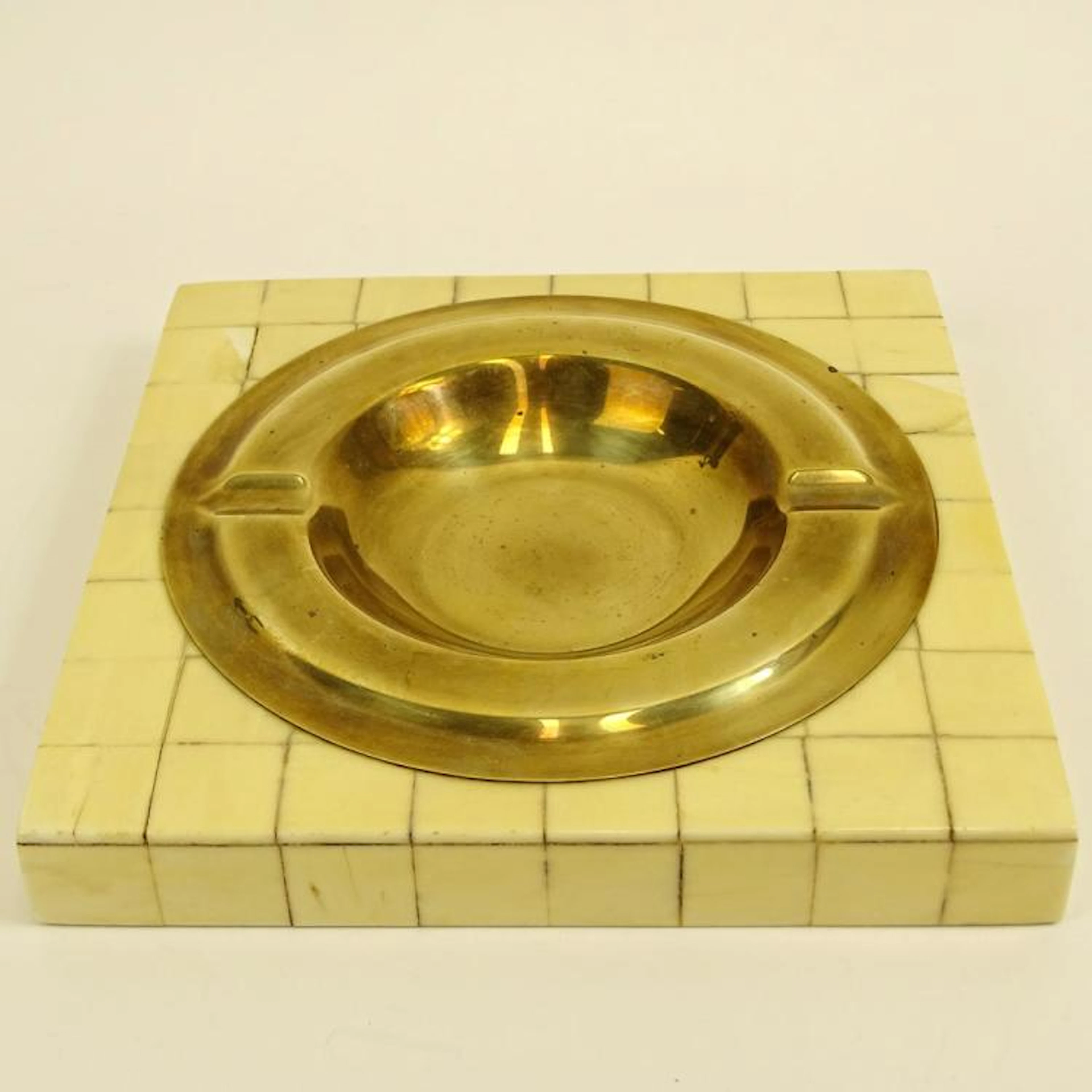 Circa 1980's Karl Springer, American (1931-1991) Bone Veneer and Brass Ashtray. Signed Made in Colombia. Minor Losses, wear. Measures 1" H x 8-1/4" x 8-1/4"