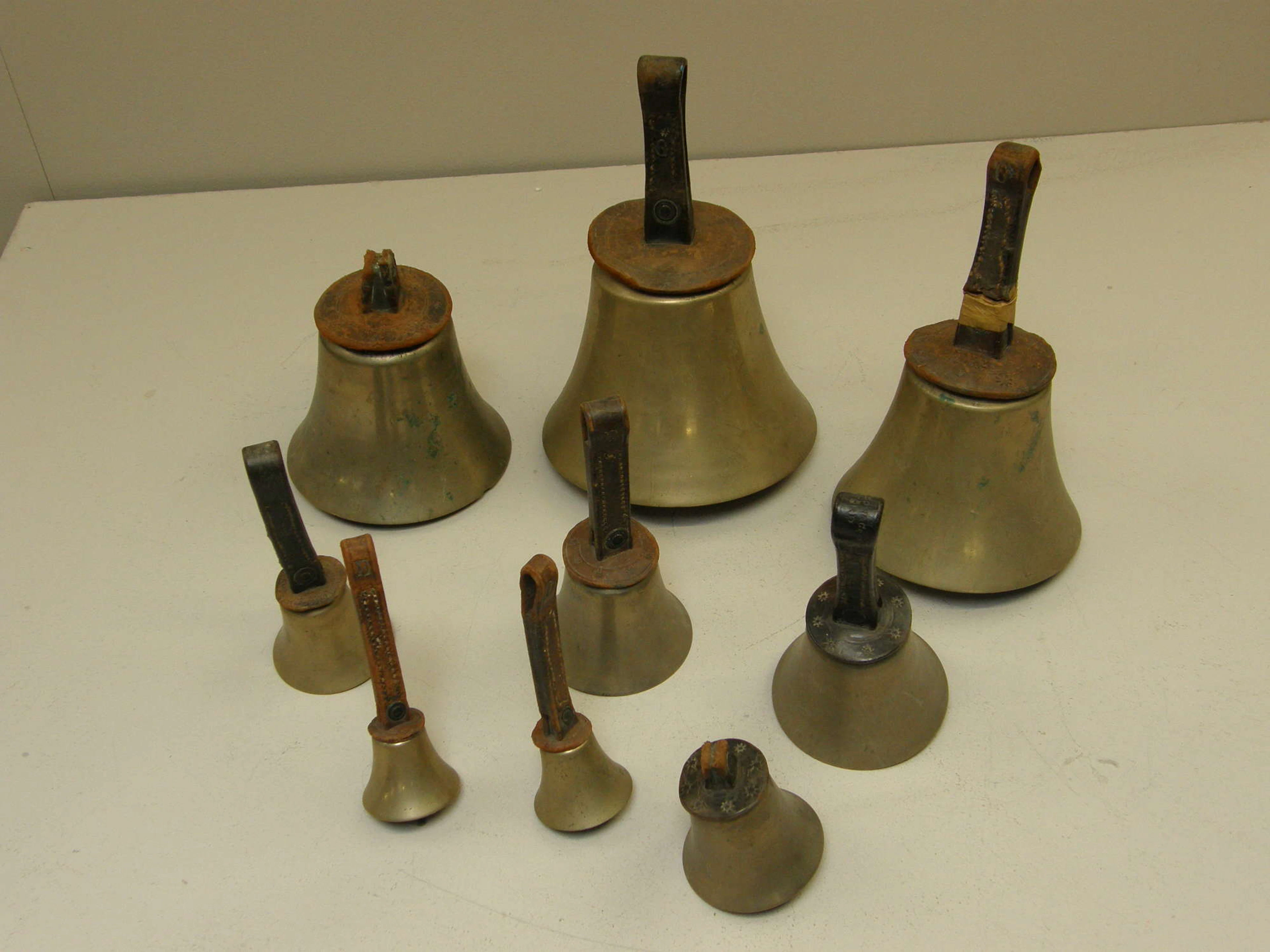 Nine handbells two marked Mears and another marked J Shaw Bradford on the leather strap PROVENANCE; Henk Huffener A Cabinet of Curiosities