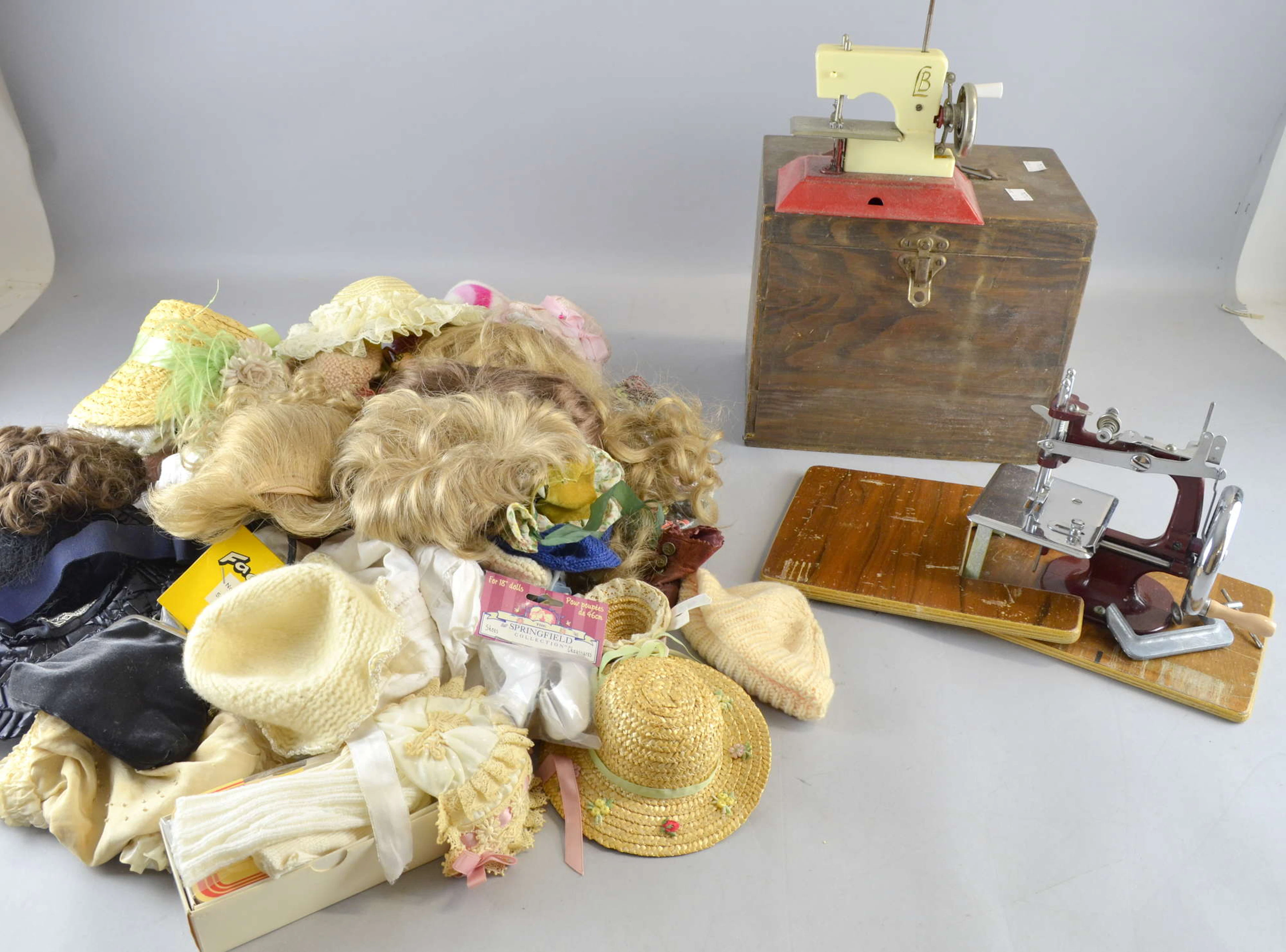 Two toy sewing machines and collection of doll's clothes