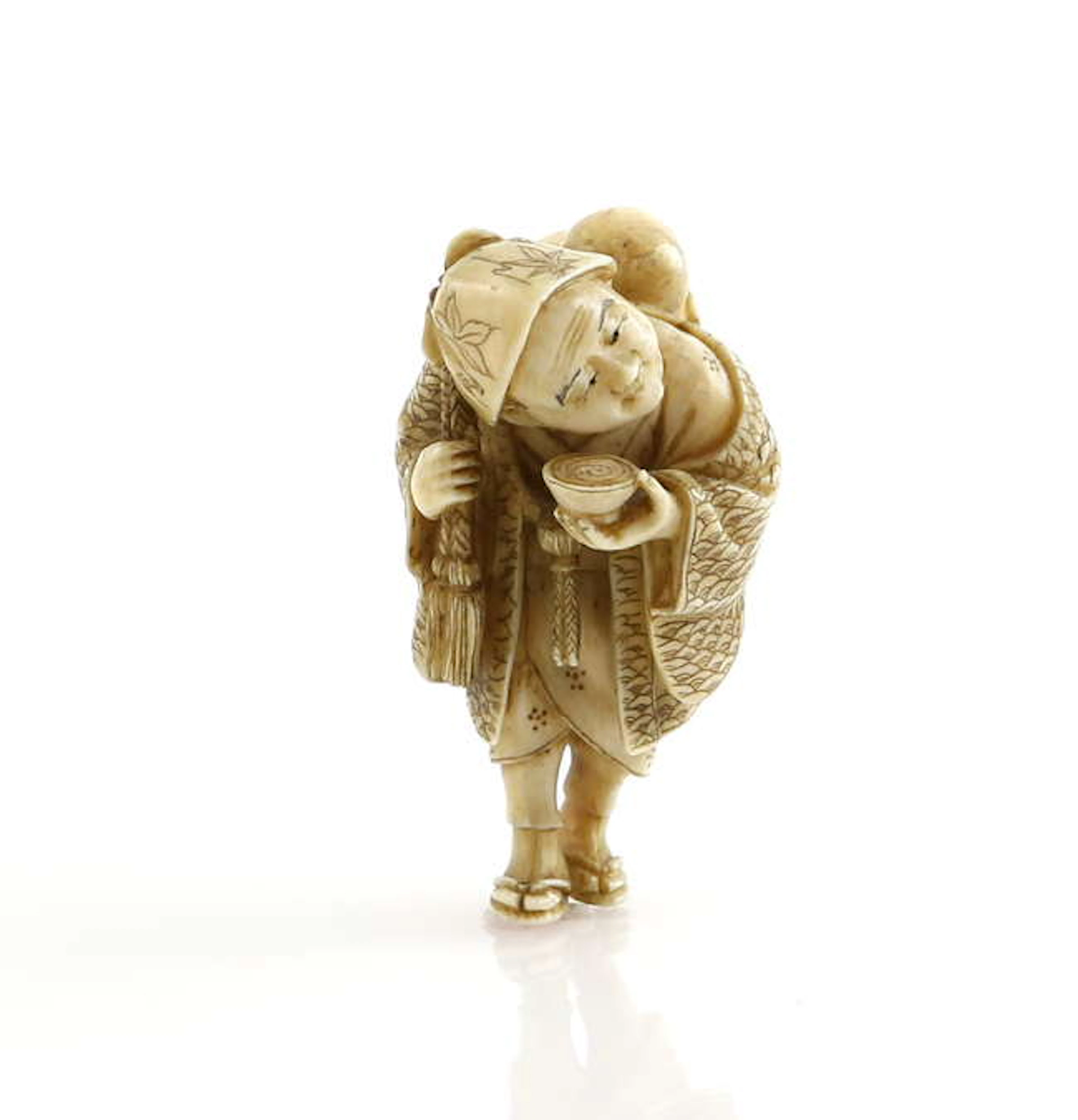 A stained ivory netsuke carved as a traveller wearing...