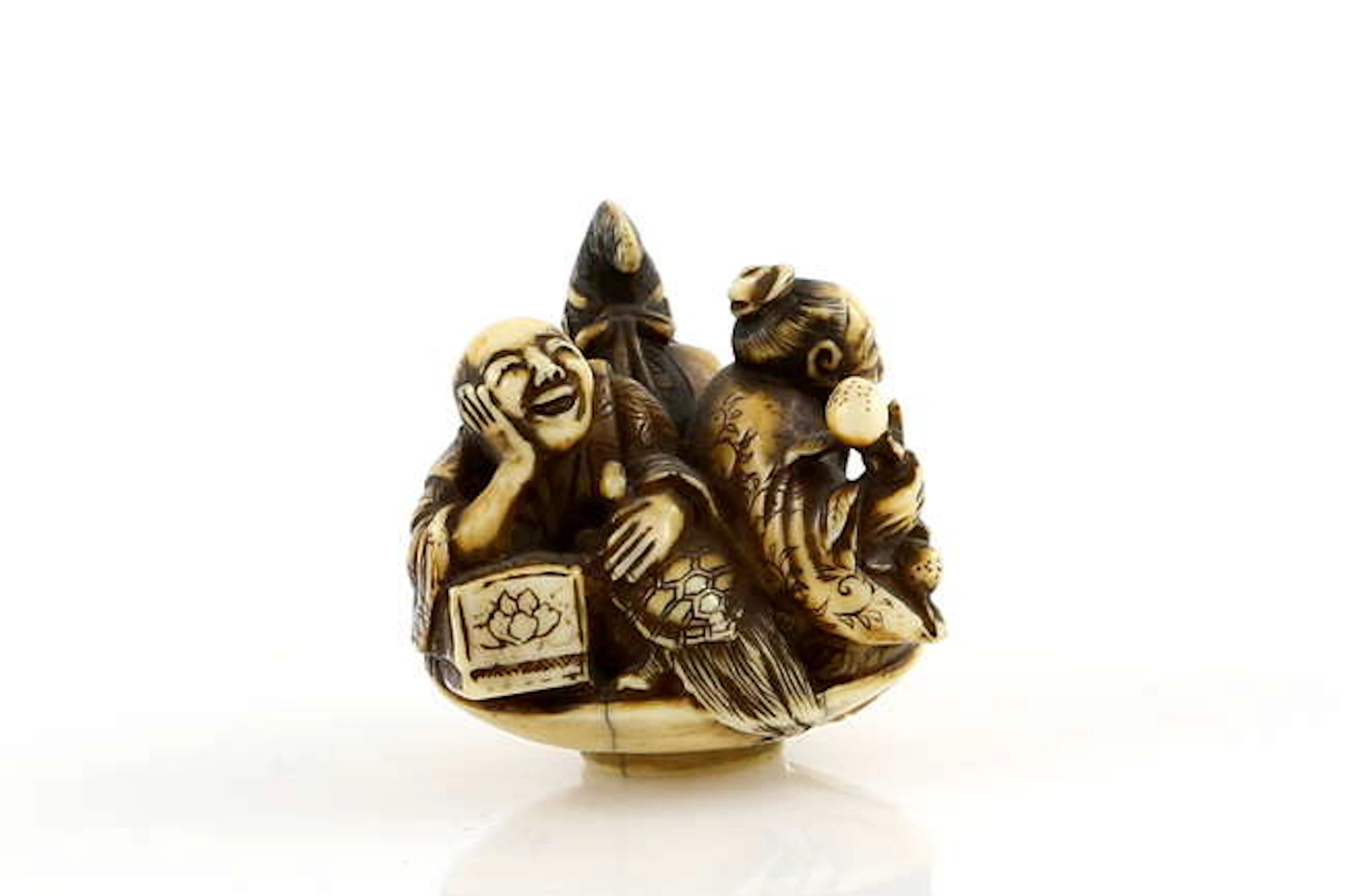 An ivory netsuke of three men in a massive sakazuki