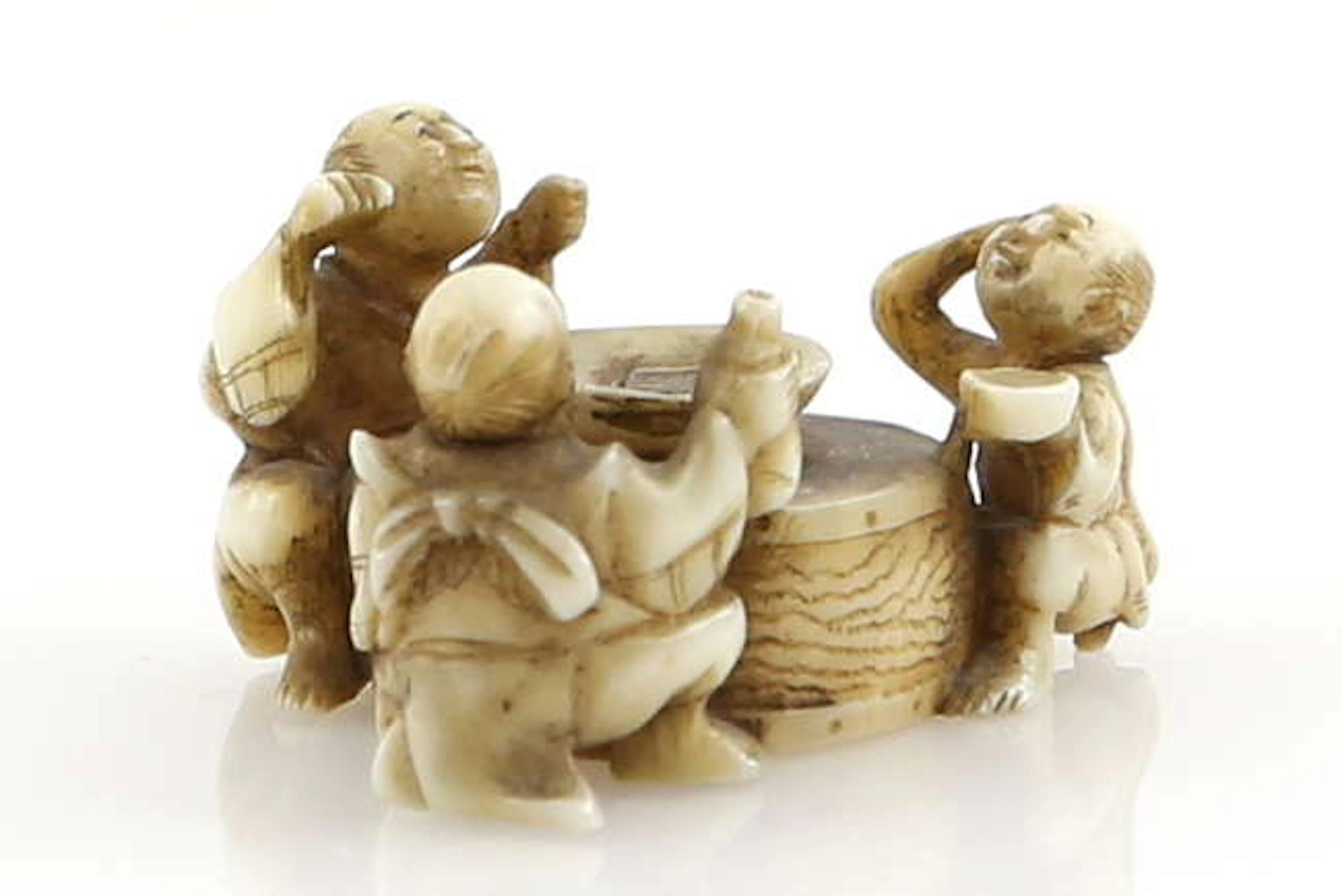 A small stained ivory netsuke of three sake tasters