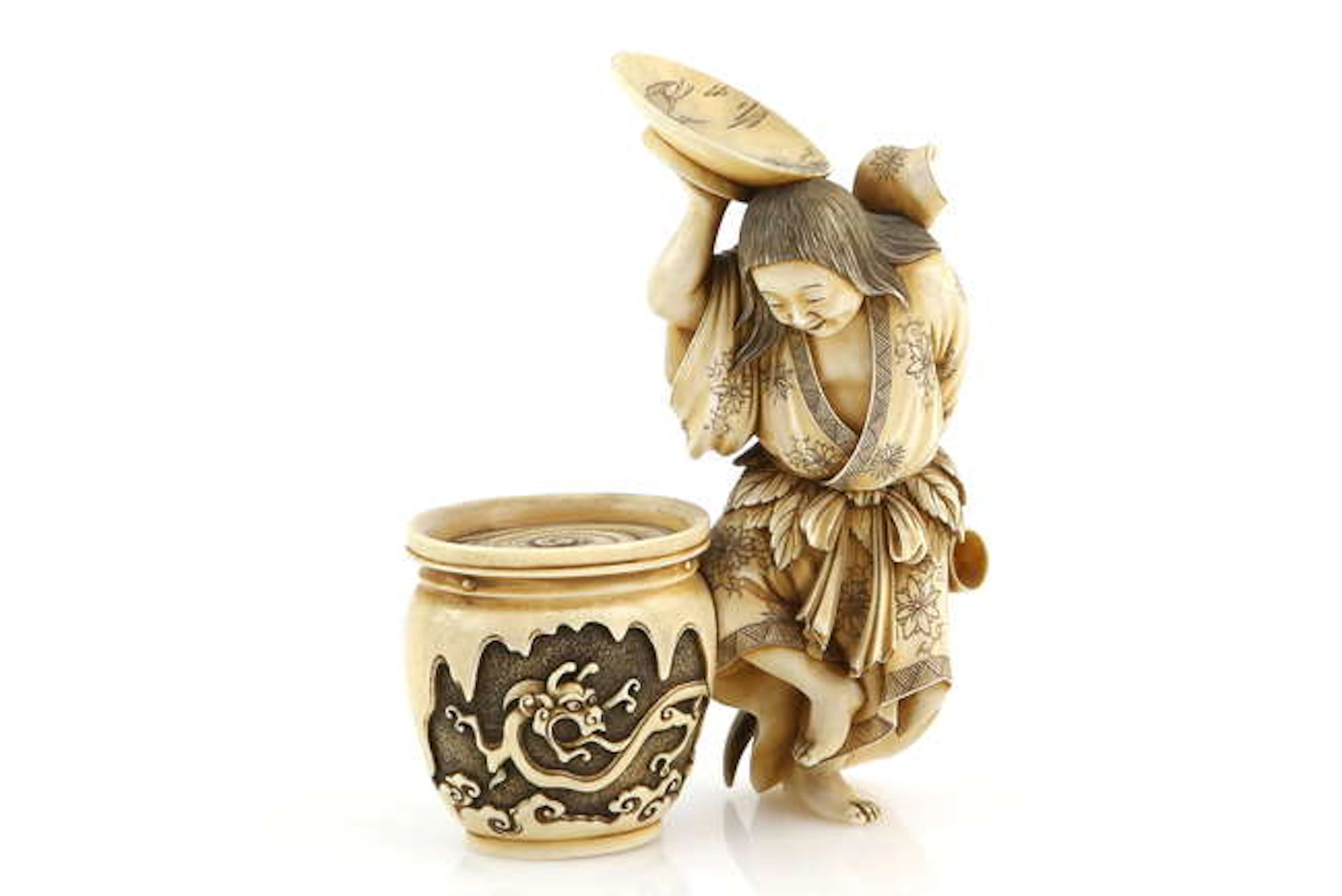 A stained ivory okimono carved as a dancing Shojo holding...