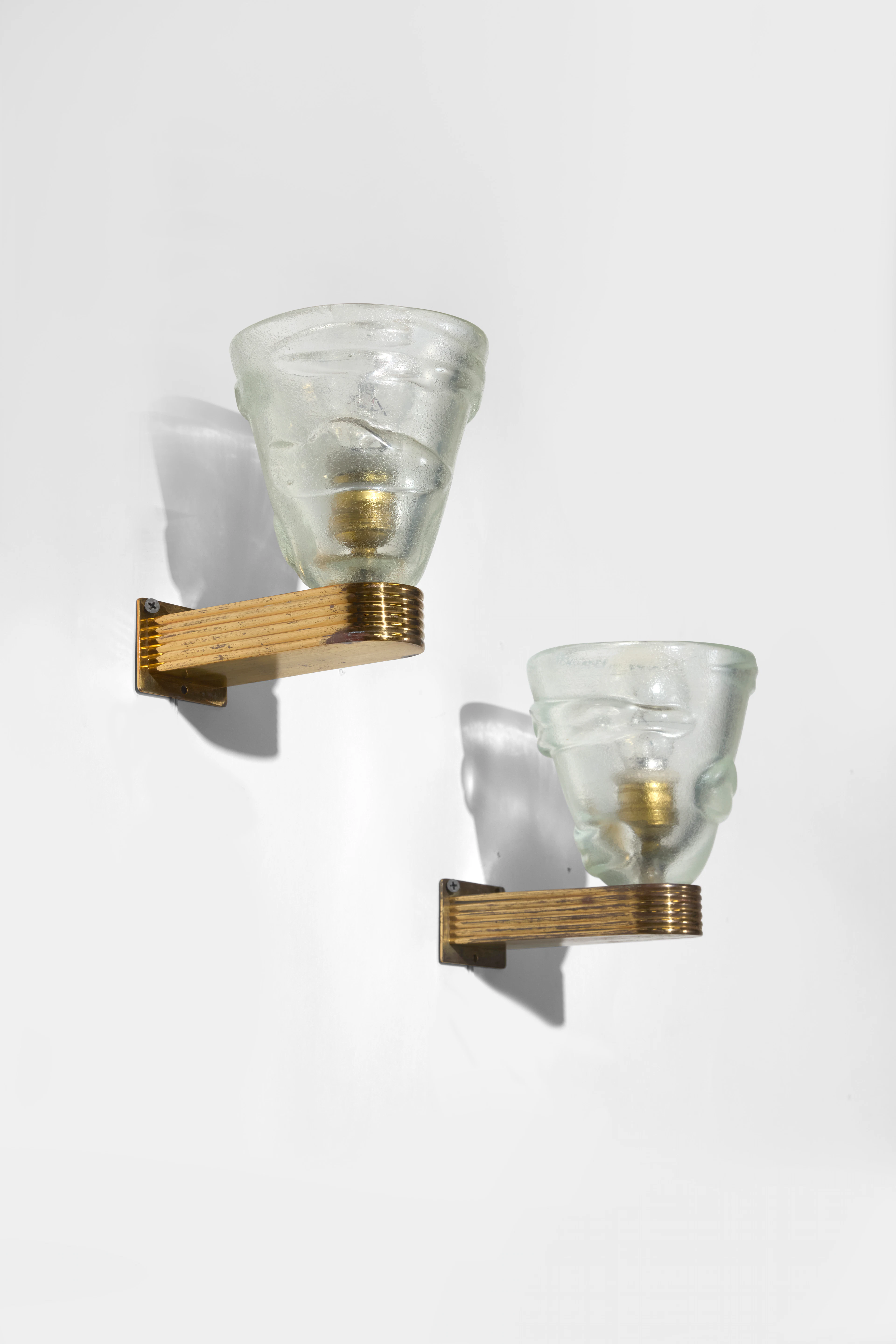 A pair of brass and Murano molded glass wall lamps by...