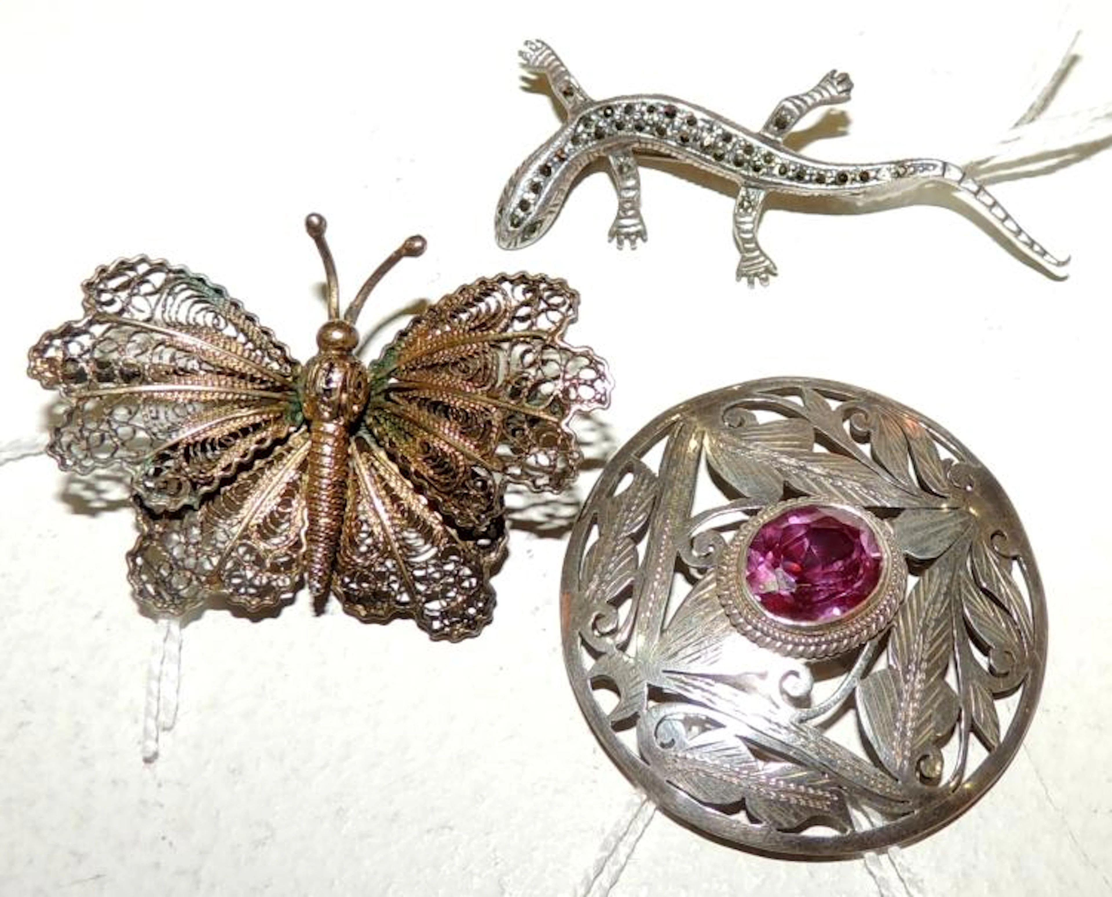 THREE BROOCHES in silver with butterfly shapes, lizard and vegetal decoration.