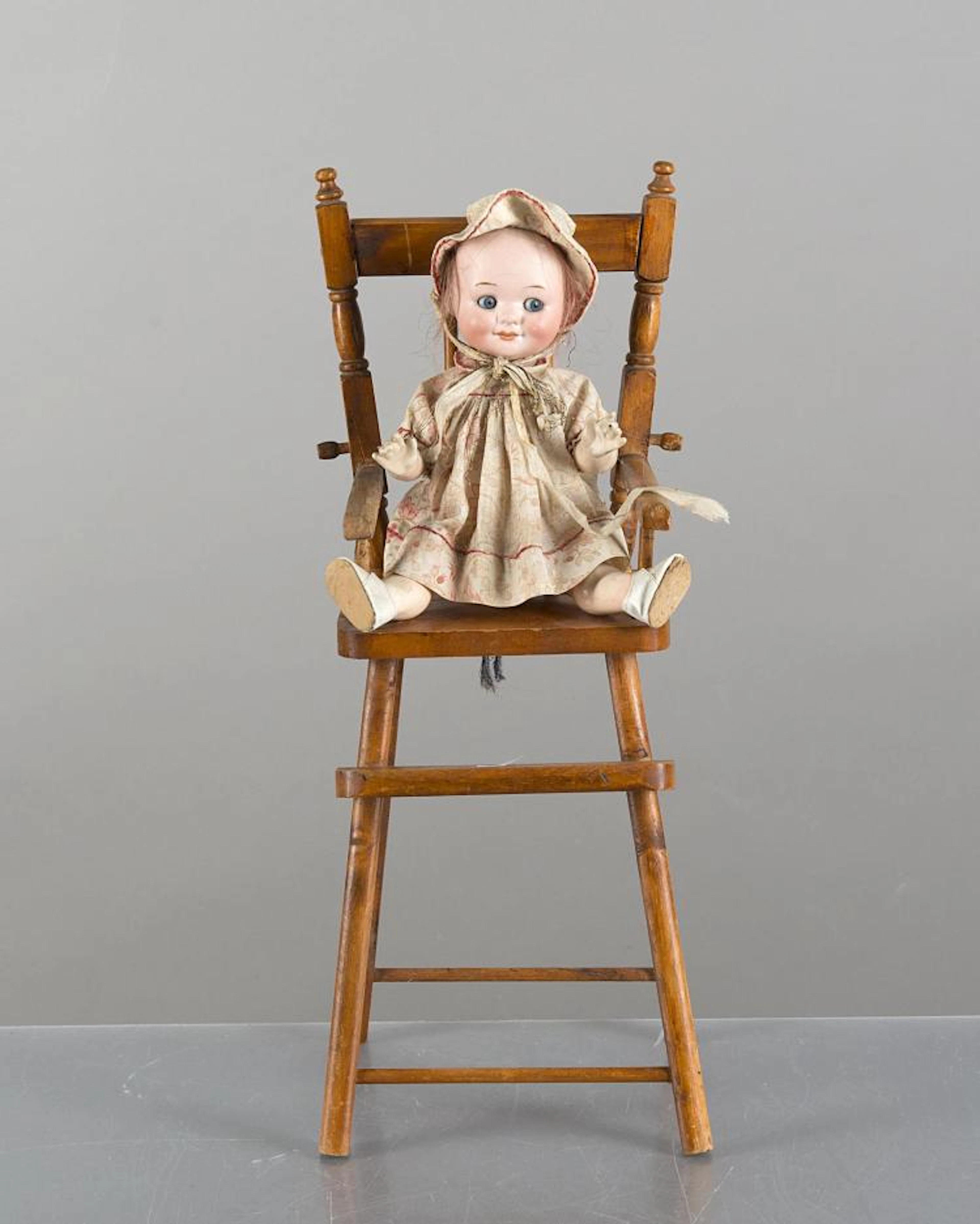 Une poupée Gogly Armand Marseille 323 sur sa petite chaise en bois.