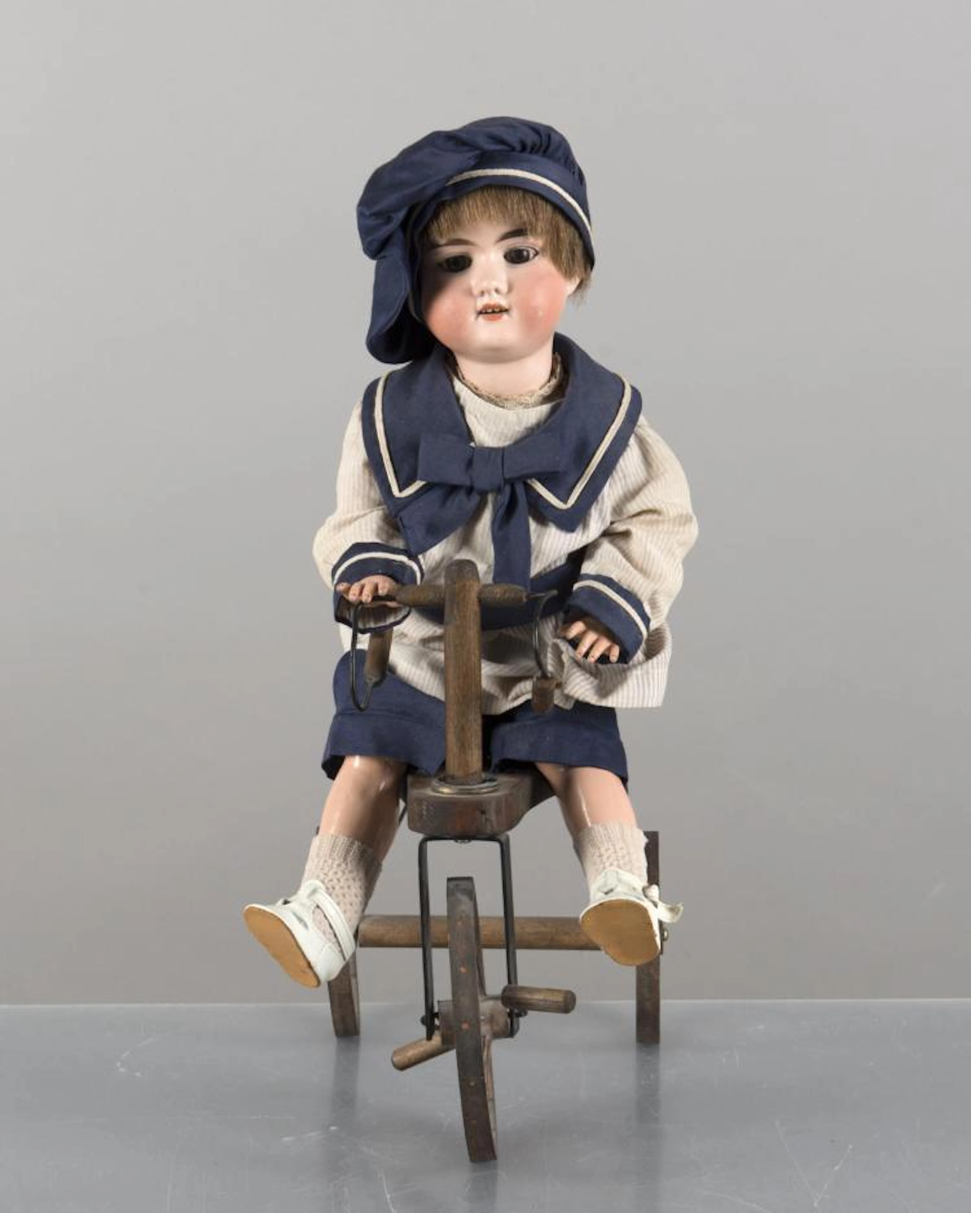 Poupon Armand Marseille tête en biscuit sur son tricycle.