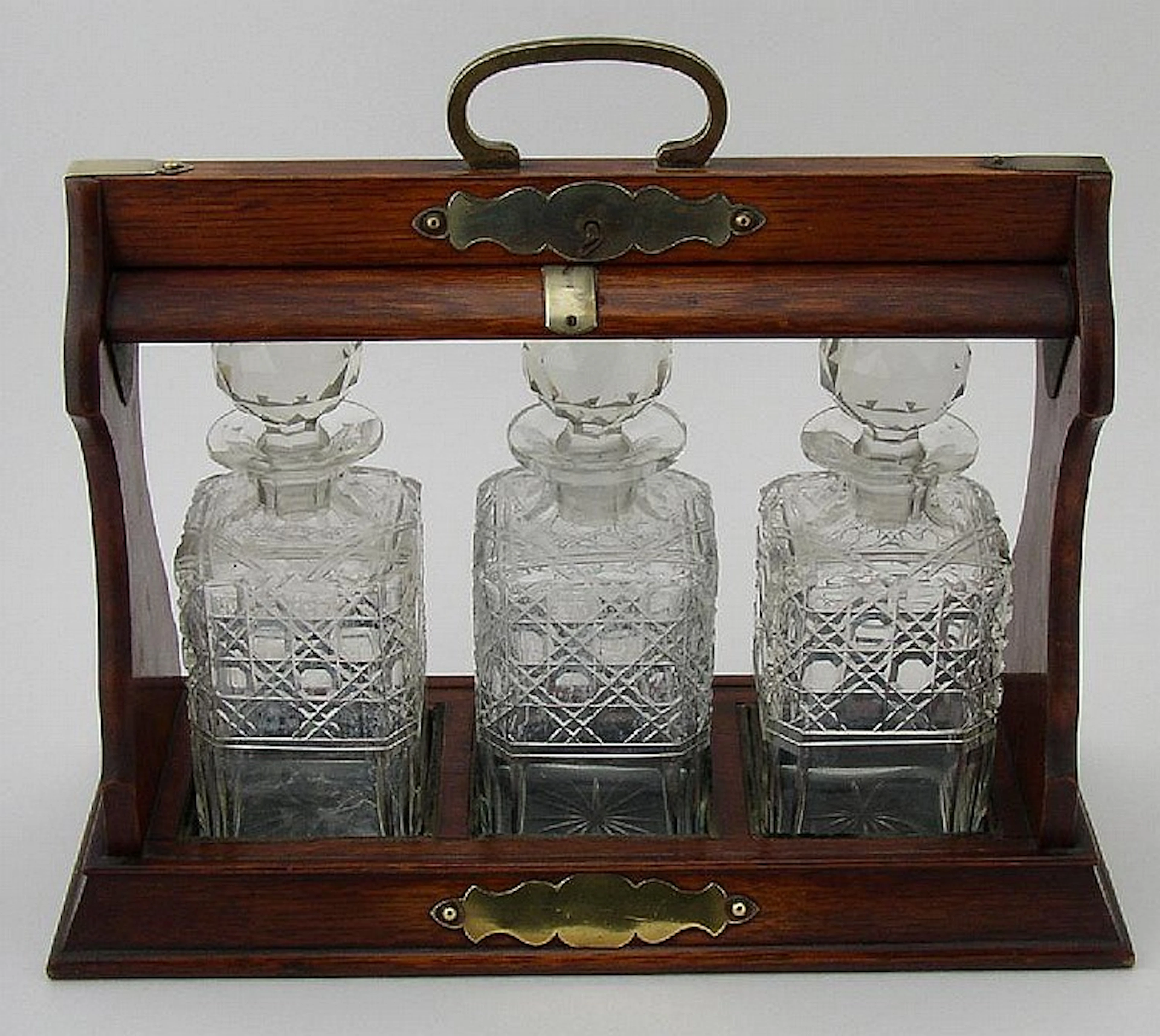 An Edwardian oak Tantalus with brass furniture and
